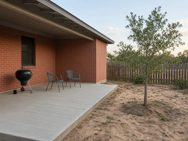 Broom-finish back patio under a porch roof at a brick ranch house