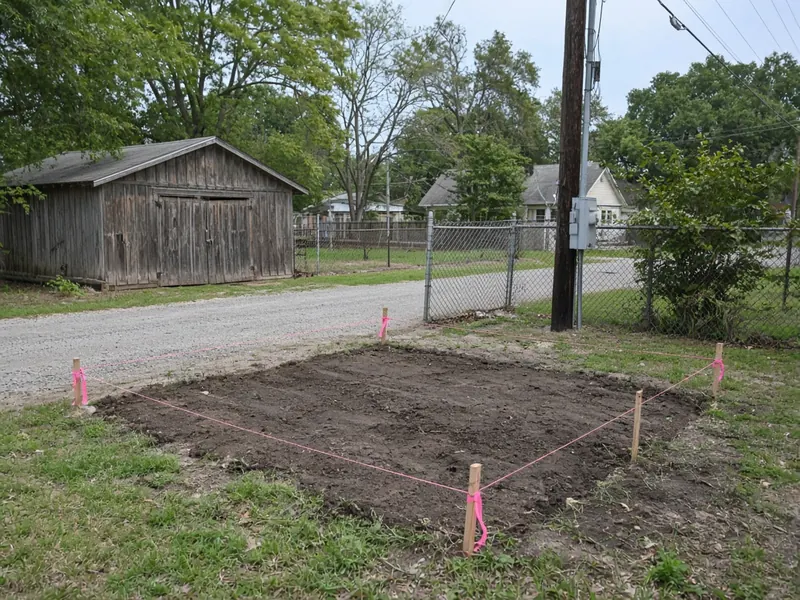 New shop pad staked out with string lines beside a gravel alley, Merkel, TX