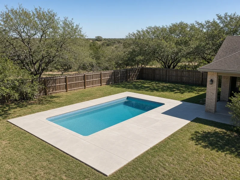 Pool and light concrete deck set well back from the fence and house