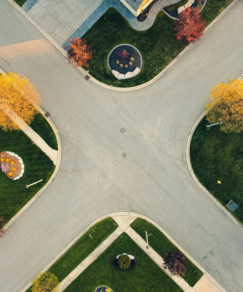 Overhead view of a concrete street intersection with curbs, gutters, sidewalks and curb ramps at each corner