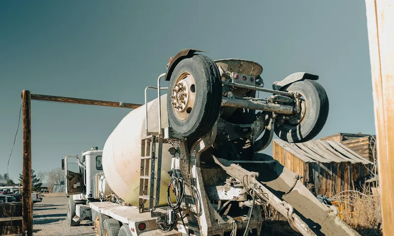 Ready-mix concrete truck with its chute extended at a gravel job site under a clear sky
