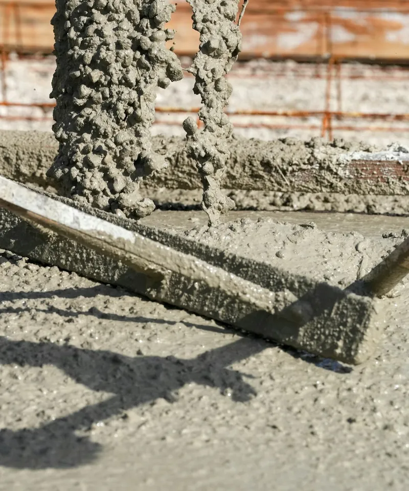 Concrete flowing from a chute onto a fresh slab while a straightedge screed levels the surface